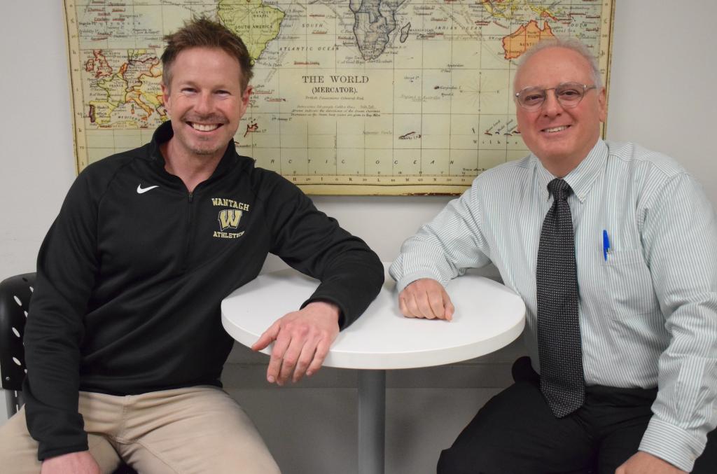 two men sitting at a small circular table smiling